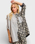 Woman wearing a floral patterned kimono-style garment over a striped shirt on a white background