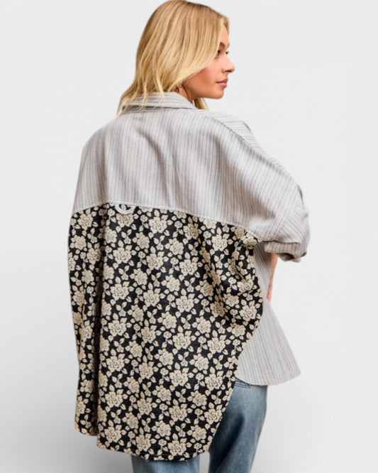 Woman wearing a floral patterned shirt over a striped shirt on a white background