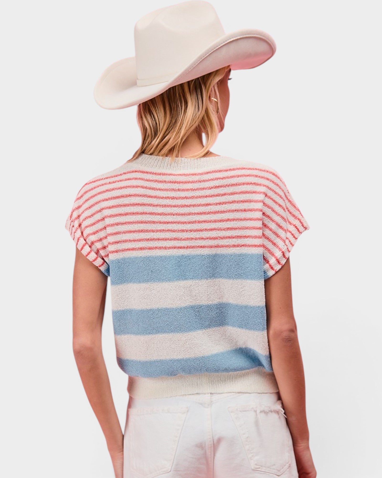 Woman wearing a striped sweater and wide-brimmed hat on a plain background