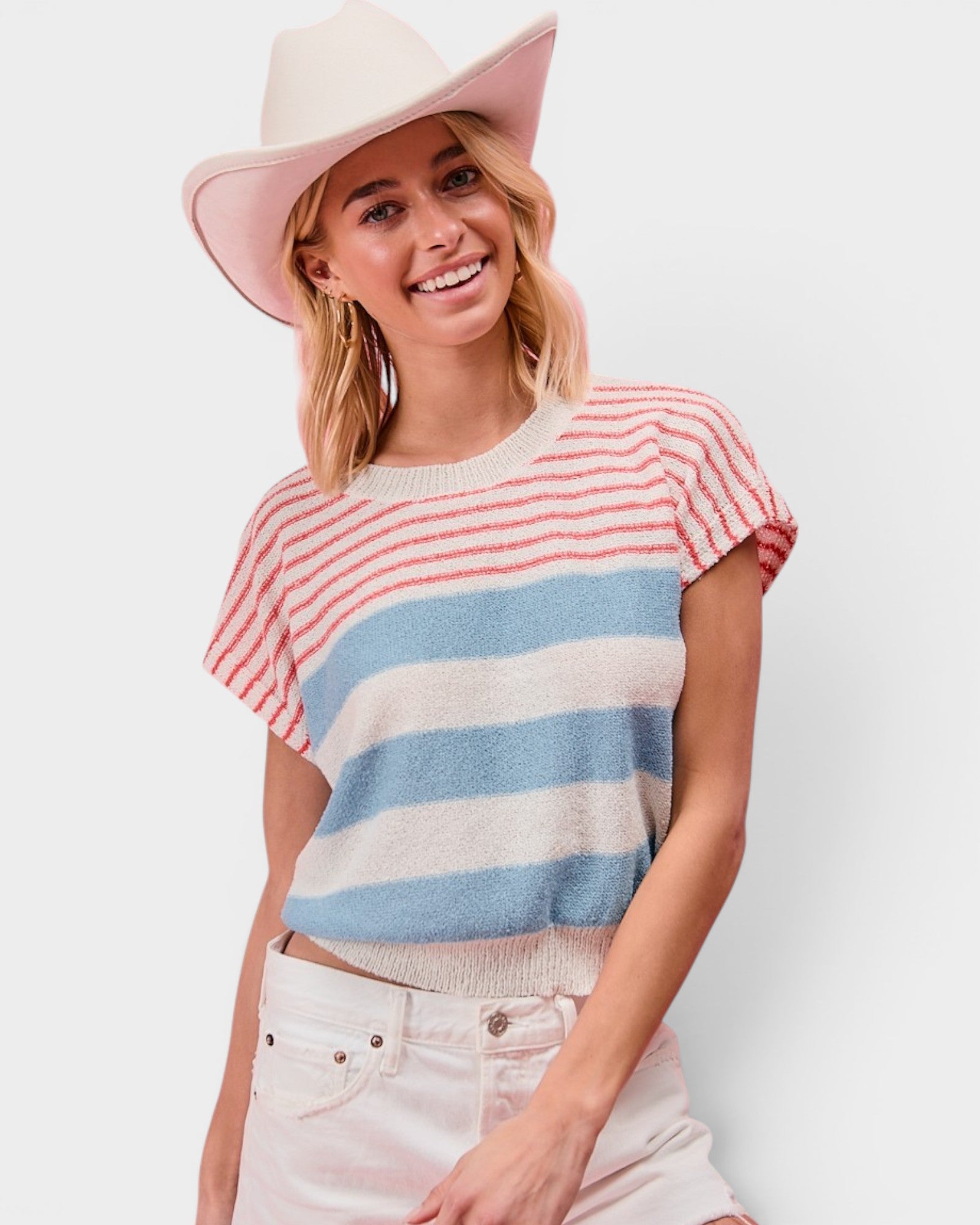 Woman wearing a striped sweater and wide-brimmed hat on a plain background