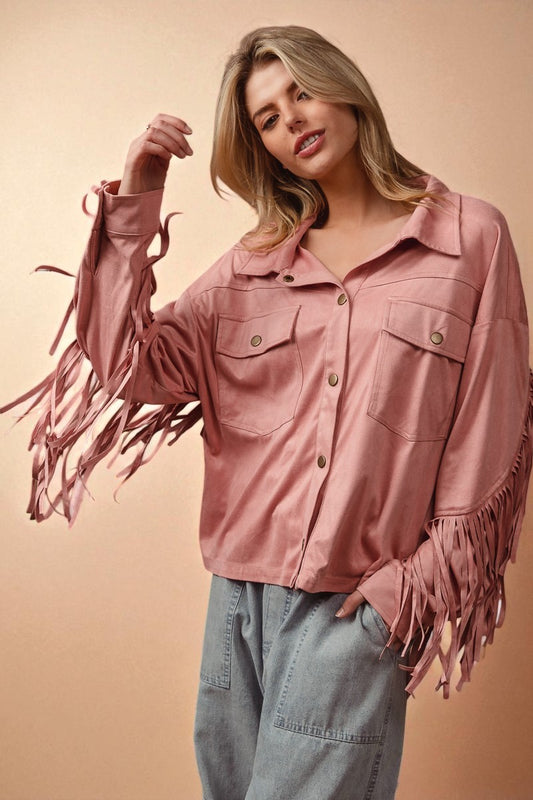 Woman wearing a pink fringed jacket against a beige background