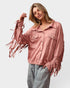 Woman wearing a pink fringed jacket on a white background