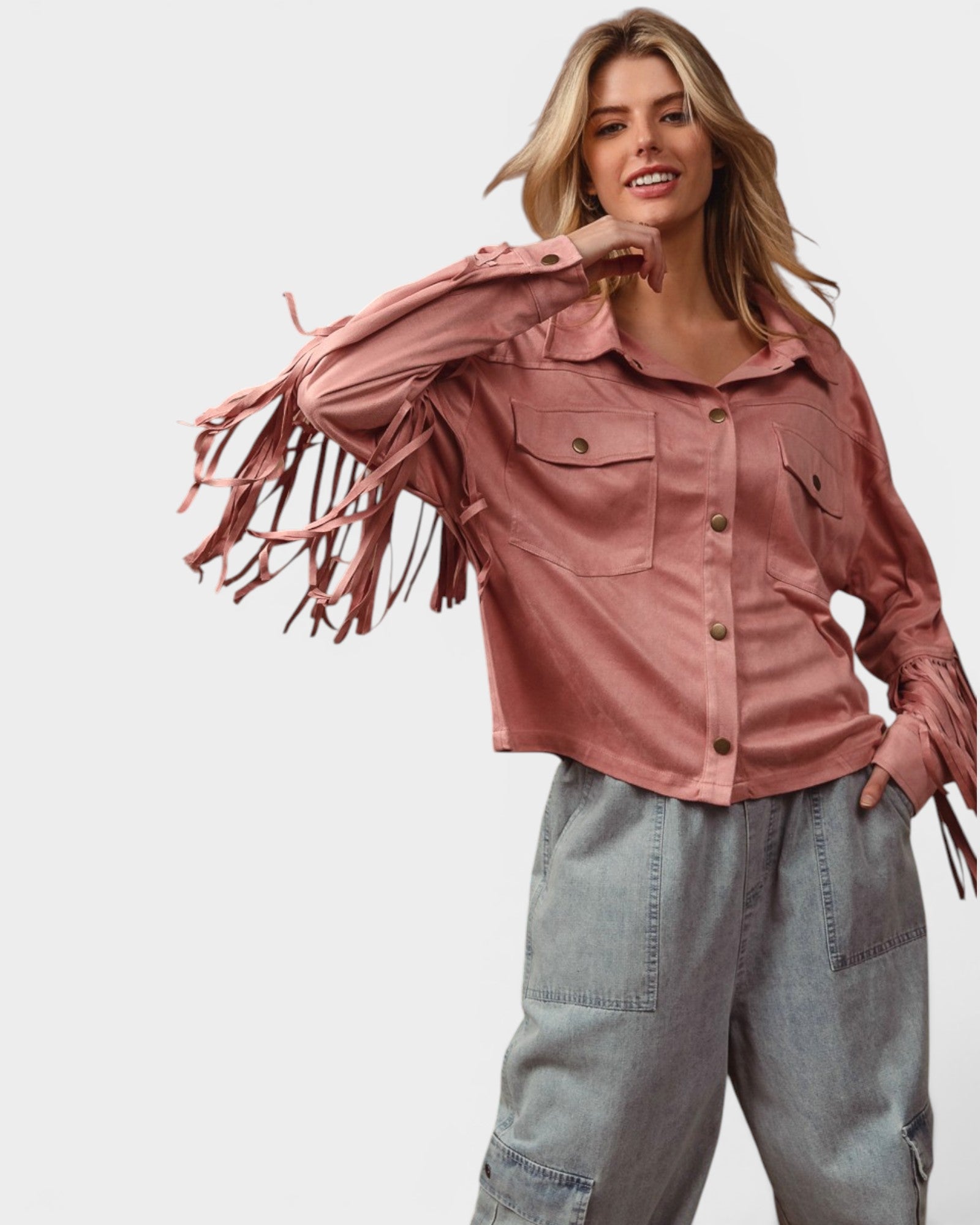 Woman wearing a pink fringed shirt and light blue jeans on a white background