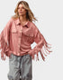 Woman wearing a pink fringed jacket on a light gray background