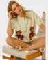 Woman wearing a white cardigan with teddy bear designs, sitting on a chair.