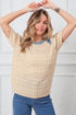 Woman wearing a beige textured sweater with blue trim against a white background