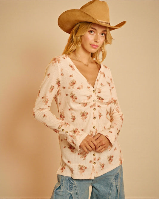 Woman wearing a floral blouse and cowboy hat against a beige background