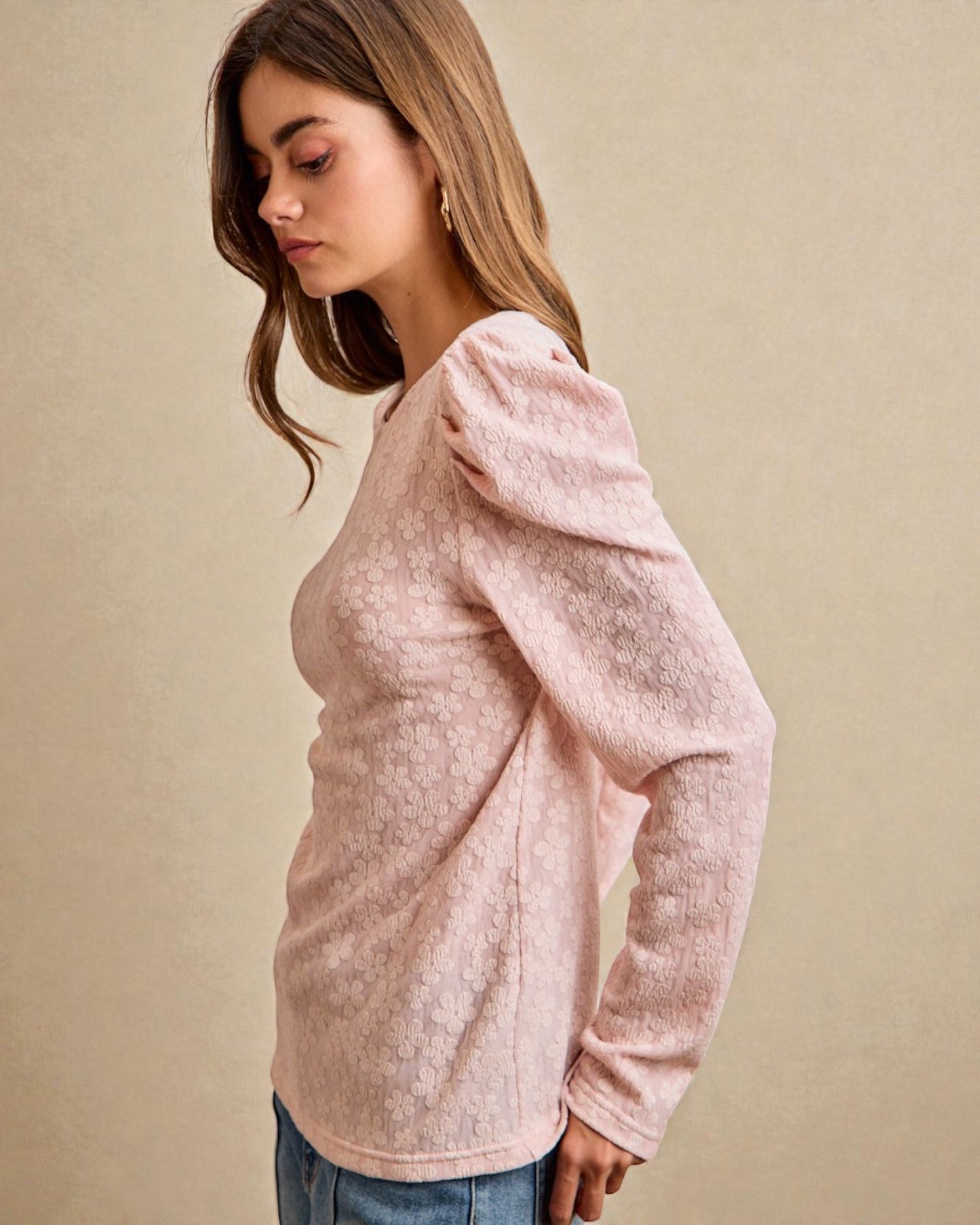 Woman wearing a pink textured sweater against a beige background