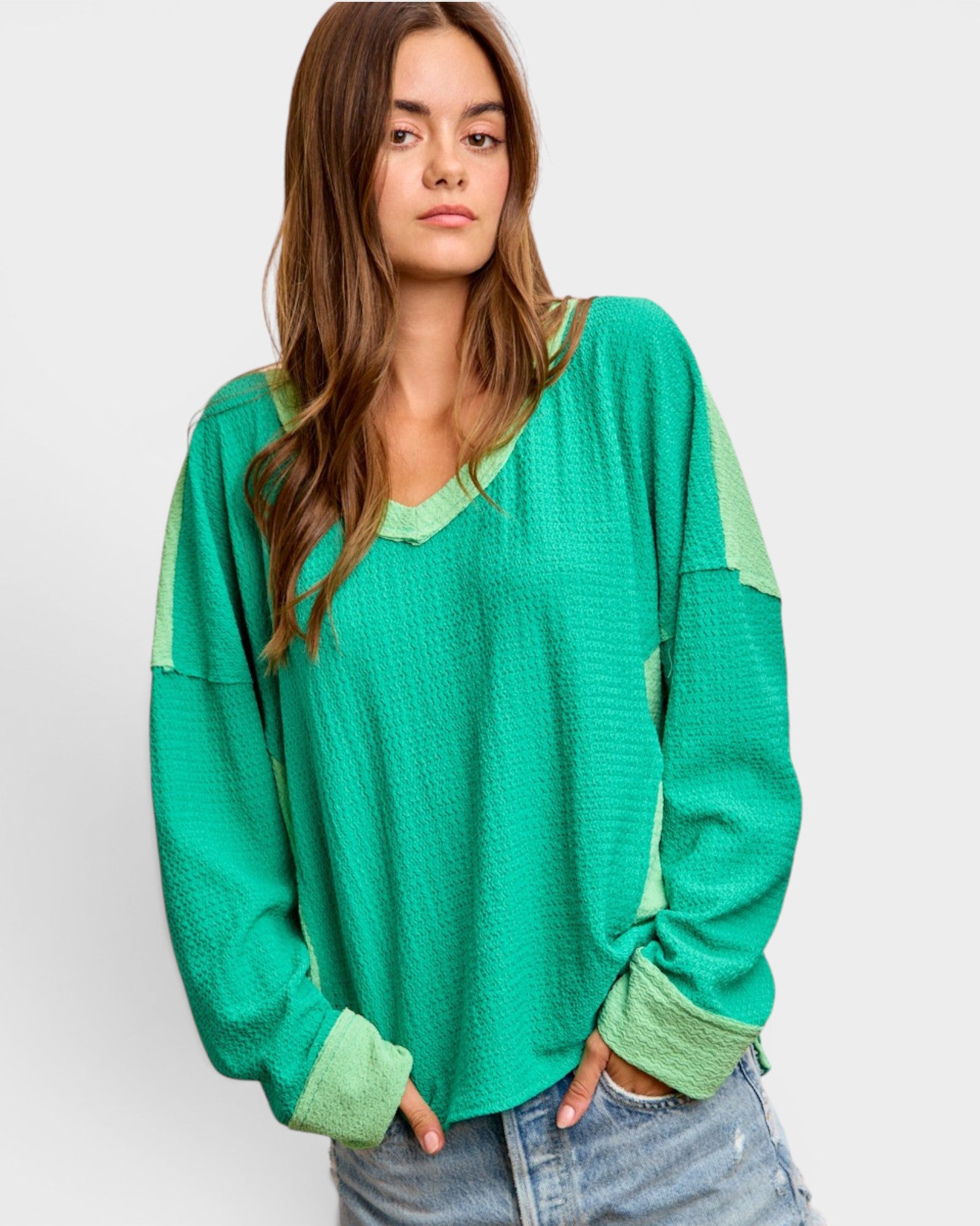 Woman wearing a green long-sleeve top with a plain background