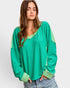 Woman wearing a green long-sleeve top with a plain background