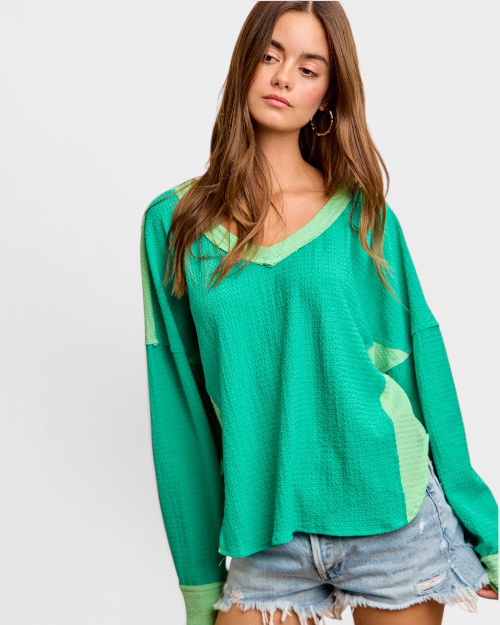 Woman wearing a green long-sleeve top with a white background