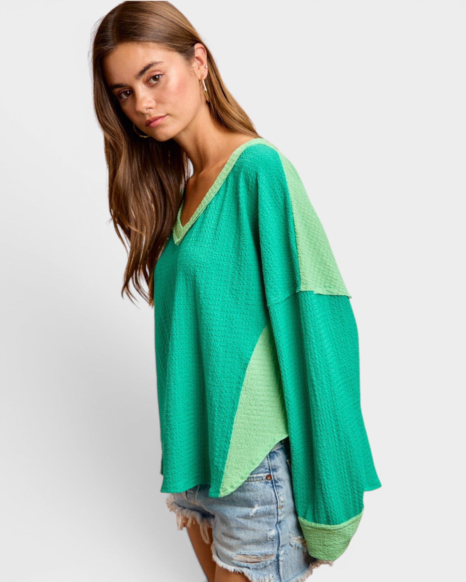 Woman wearing a green and light green color-blocked sweater on a white background