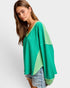 Woman wearing a green and light green color-blocked sweater on a white background