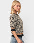 Woman wearing a floral patterned top with black trim on a white background