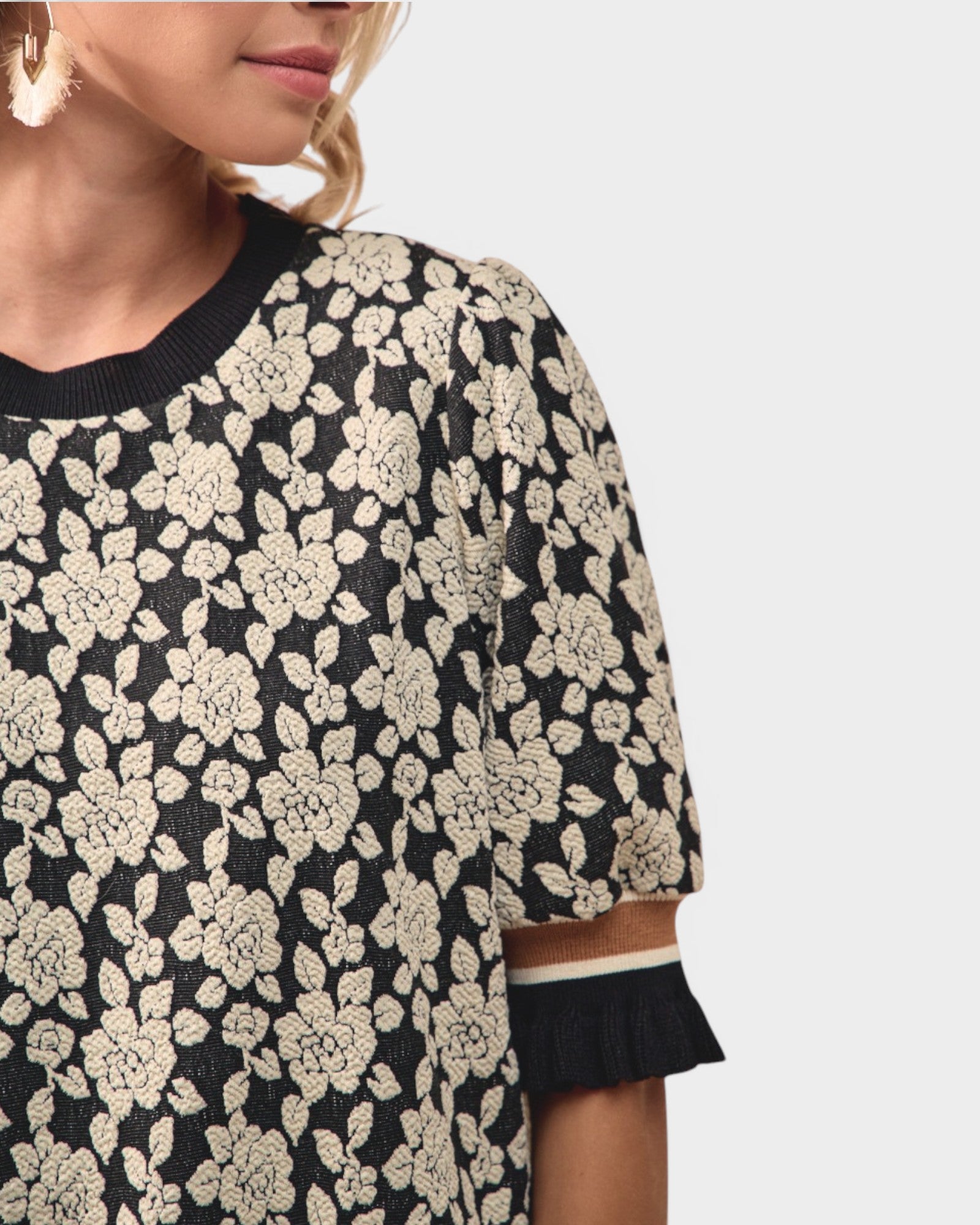 Black sweater with white floral pattern worn by a person