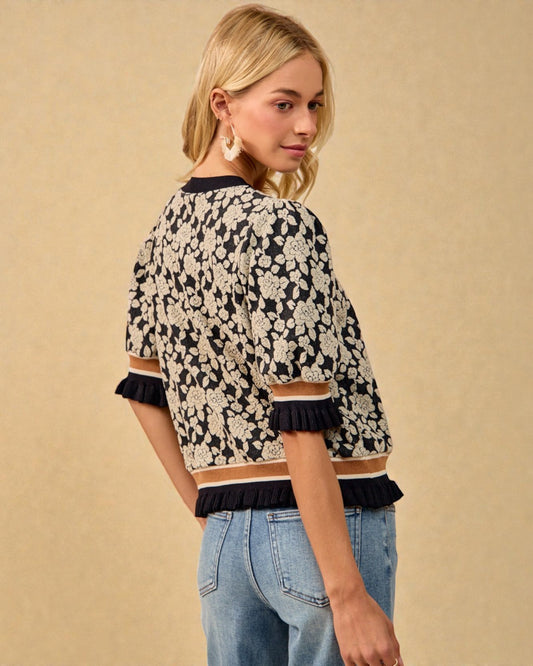 Woman wearing a floral patterned top with ruffled trim on a beige background