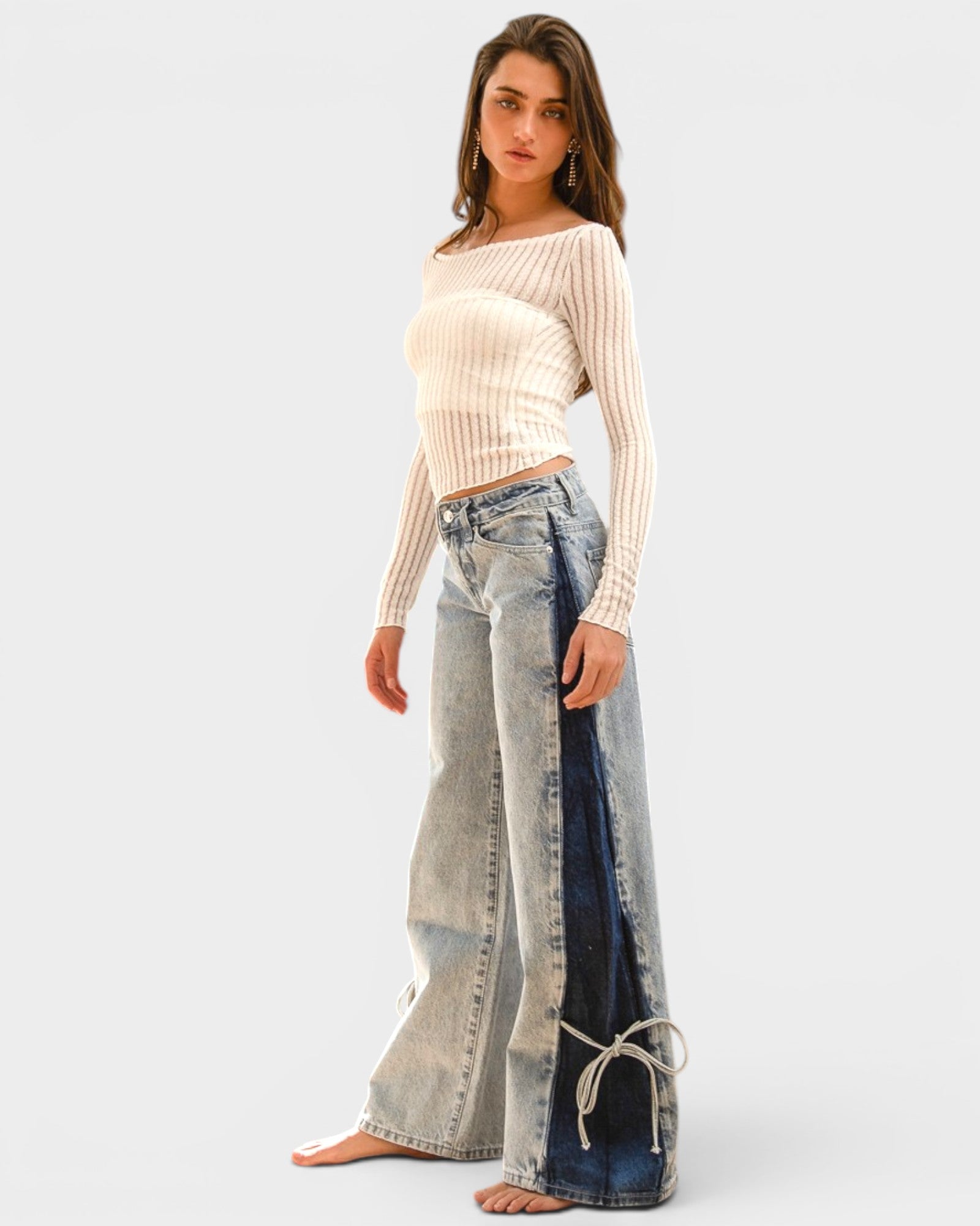 Woman wearing a beige sweater and patchwork jeans on a white background