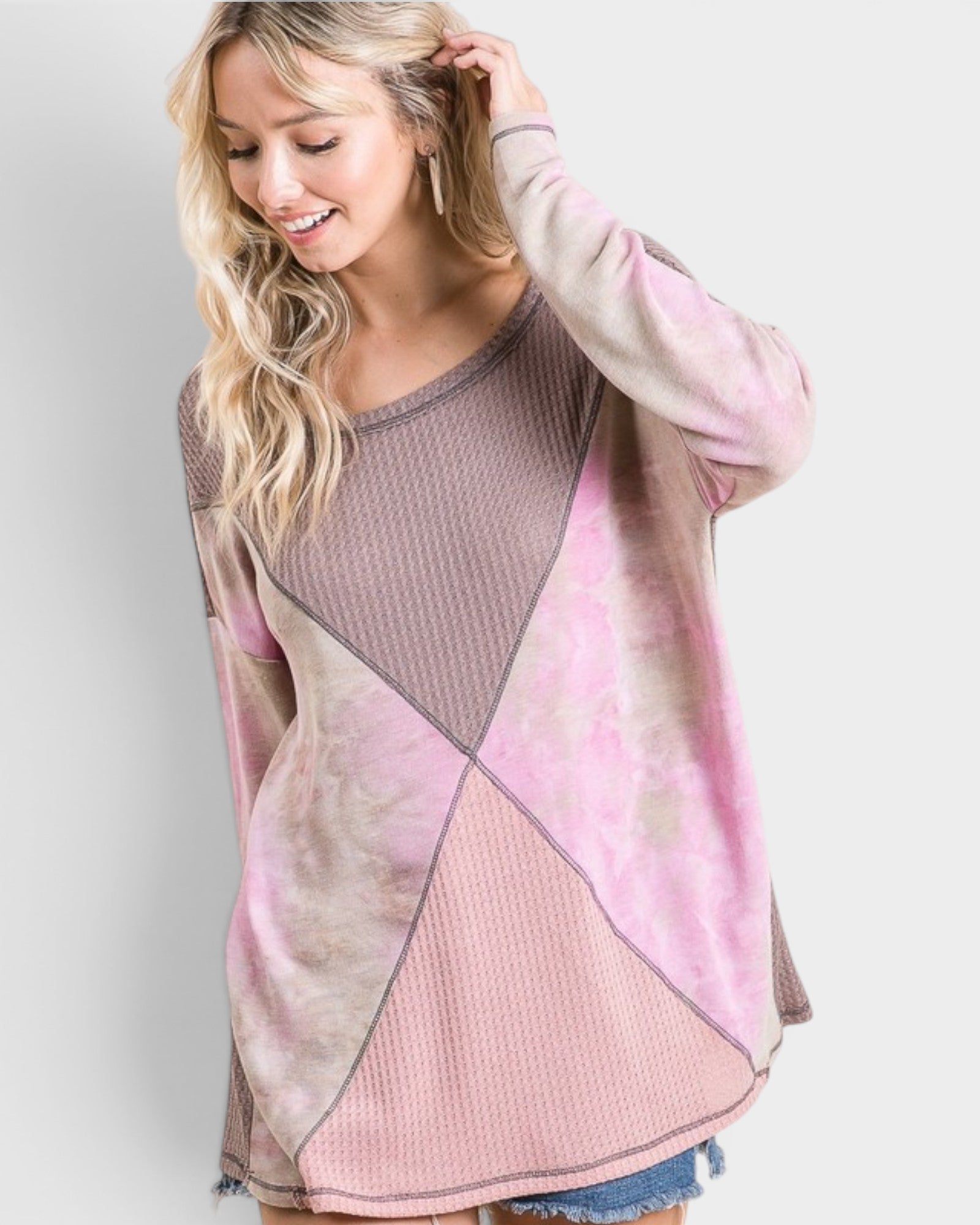 Woman wearing a pink and beige patterned sweater against a white background