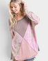 Woman wearing a pink and beige patterned sweater against a white background