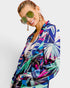 Woman wearing a colorful patterned shirt with sunglasses on a white background