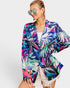 Woman wearing a colorful tropical print jacket on a white background