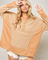 Woman wearing a beige and brown patterned top with a plain background