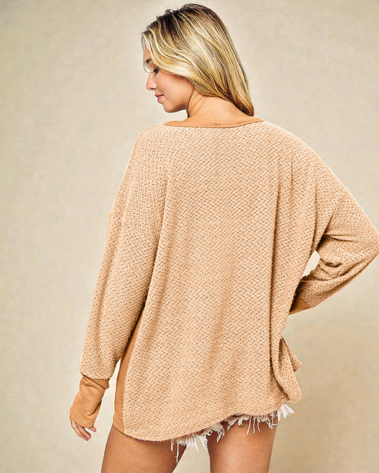 Woman wearing a beige oversized sweater with a plain background