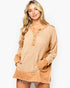 A woman modeling a tan and beige textured knit long-sleeve henley top with button details down the front, set against a plain light gray background.