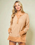 Woman wearing a beige long-sleeve top with button details on a plain background