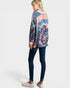 Woman wearing a tie-dye sweater and dark jeans on a white background