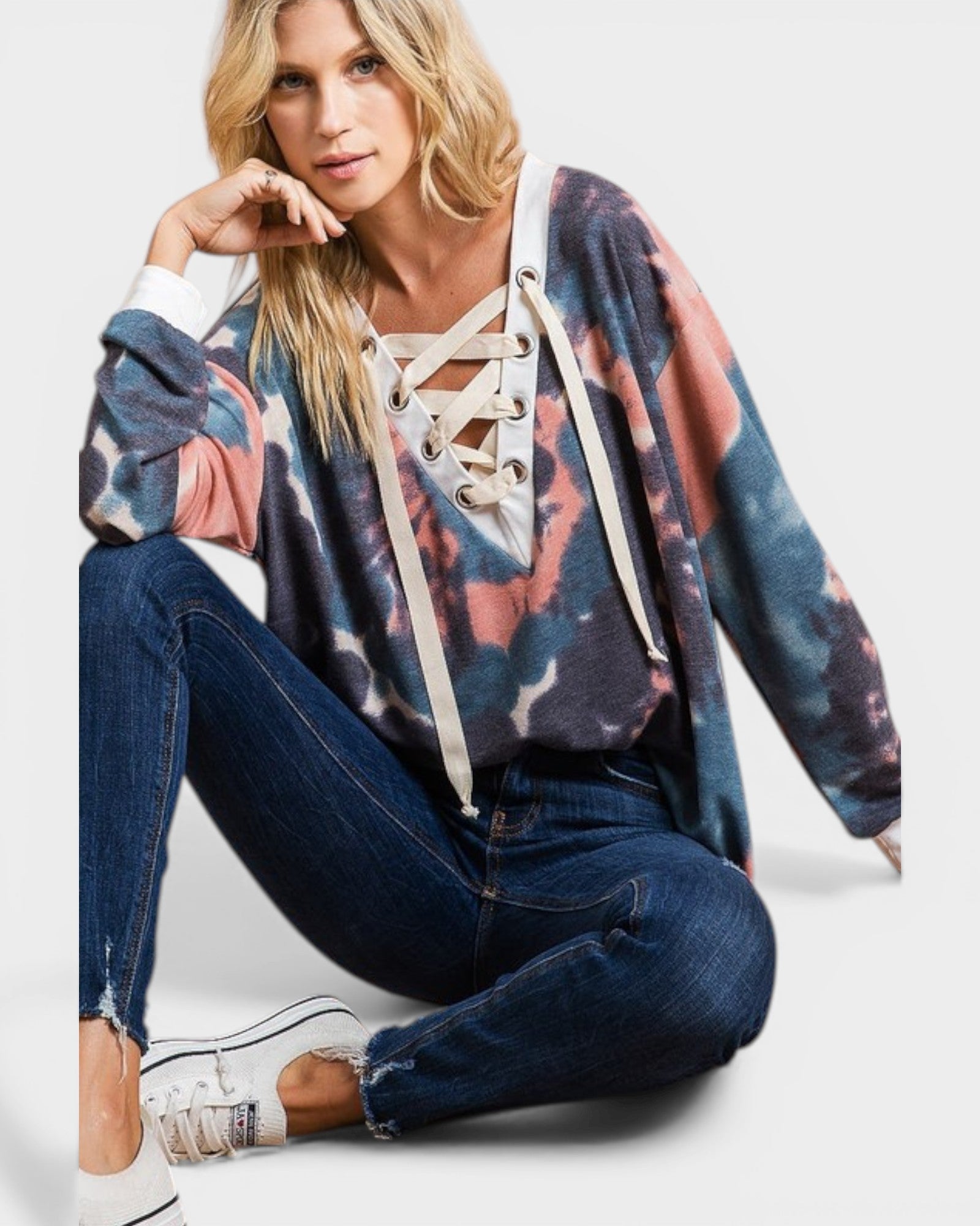 Woman wearing a colorful cardigan, jeans, and sneakers on a white background