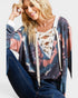 Woman wearing a colorful cardigan with a lace-up front design.