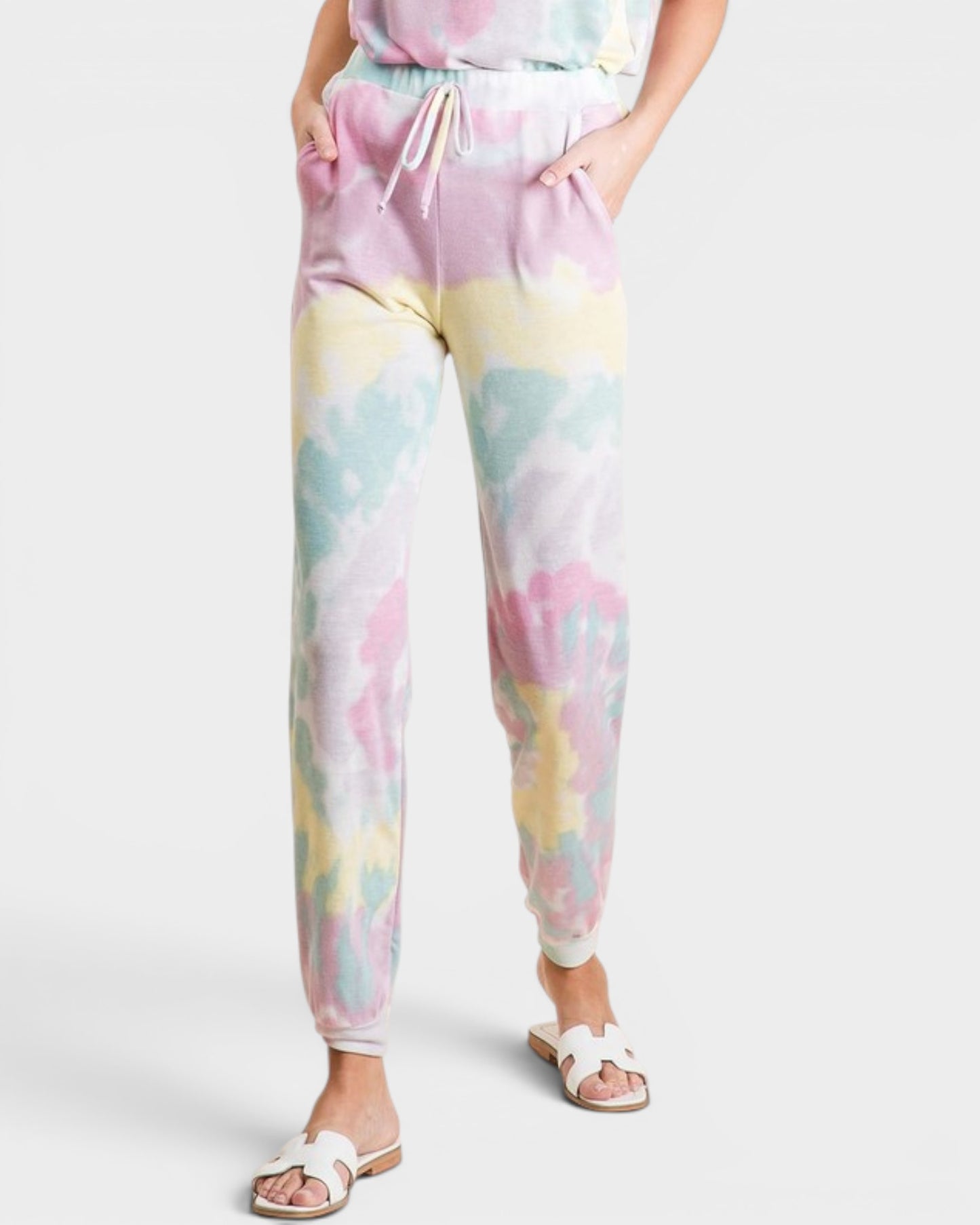 Pastel tie-dye jogger pants worn by a person on a white background