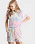 Woman wearing a tie-dye outfit with a hoodie and shorts on a plain background