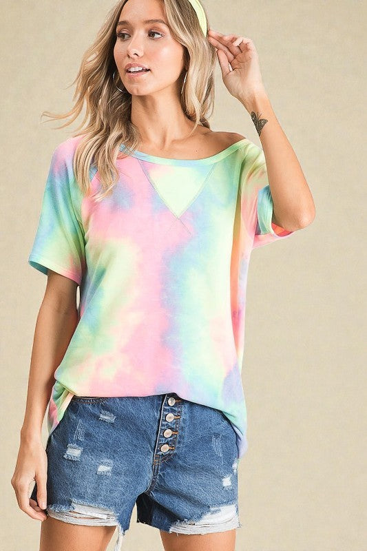 Woman wearing a tie-dye shirt and denim shorts on a beige background