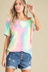 Woman wearing a tie-dye shirt and denim shorts on a beige background