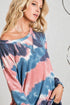 Woman wearing a tie-dye shirt with pink and blue patterns on a plain background