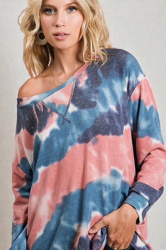 Woman wearing a tie-dye sweater with pink and blue patterns on a plain background