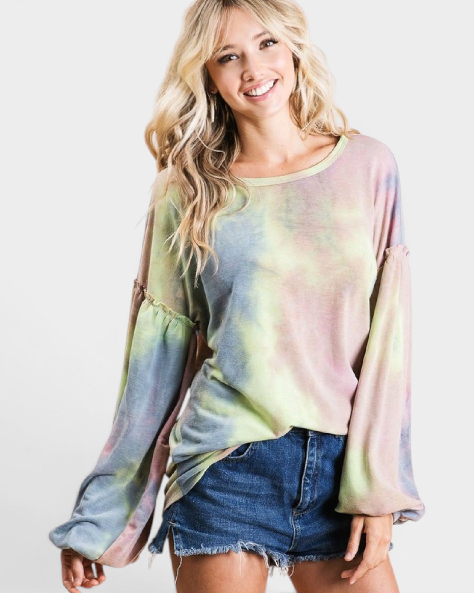 Woman wearing a tie-dye long-sleeve top and denim shorts on a white background