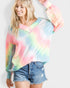 Woman wearing a colorful tie-dye sweatshirt and denim shorts on a white background