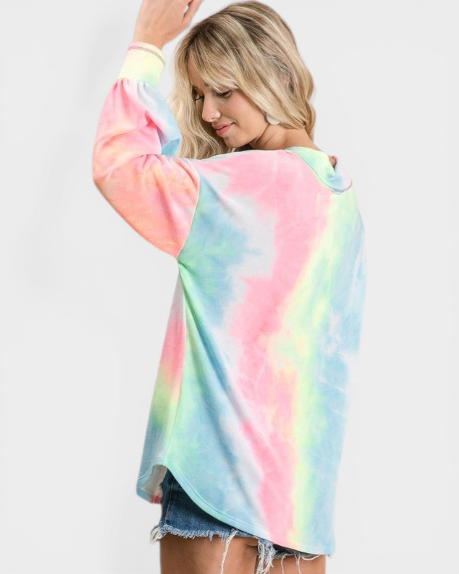 Woman wearing a colorful tie-dye shirt against a plain background