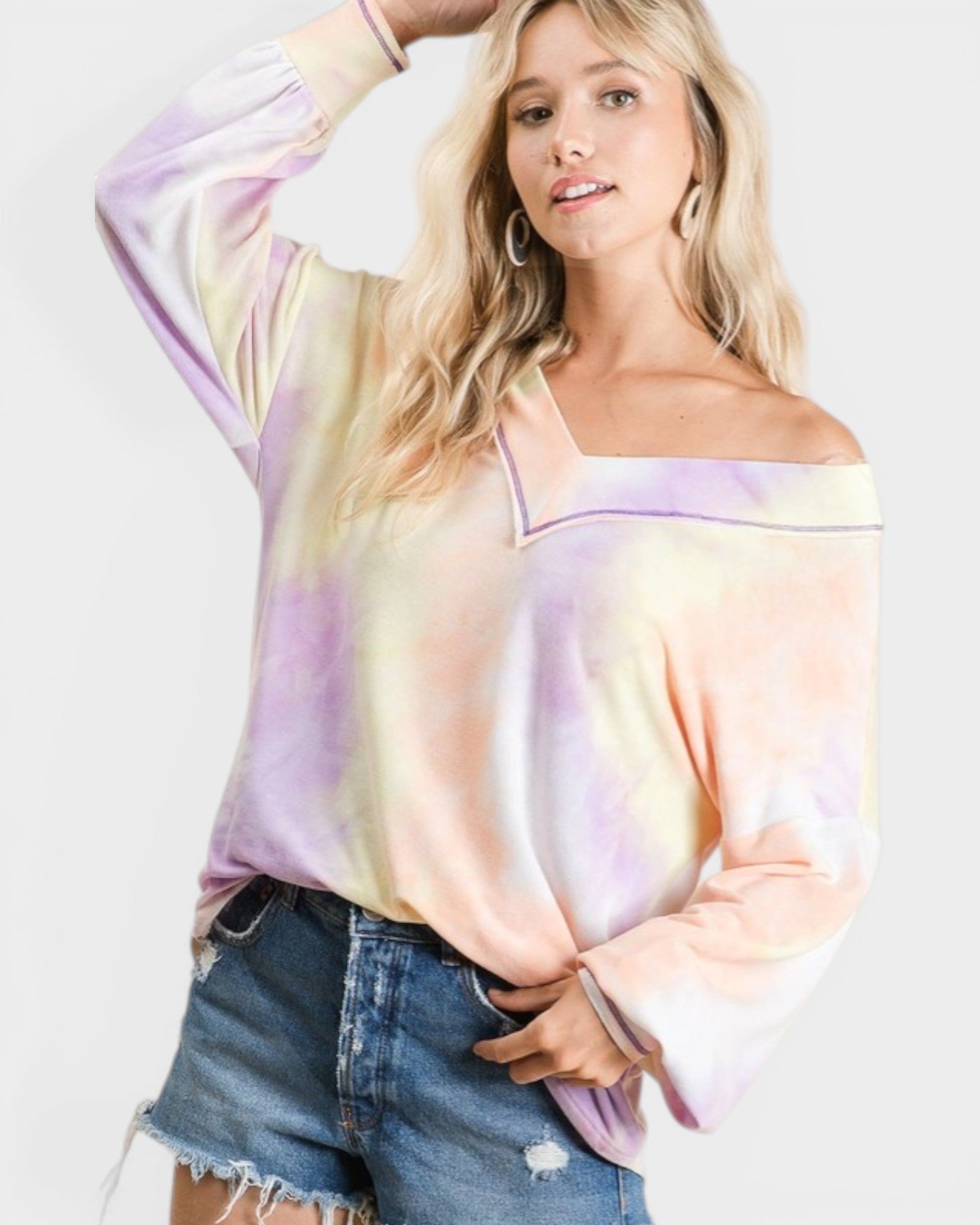 Woman wearing a tie-dye long-sleeve top and denim shorts on a white background