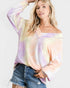 Woman wearing a tie-dye long-sleeve top and denim shorts on a white background