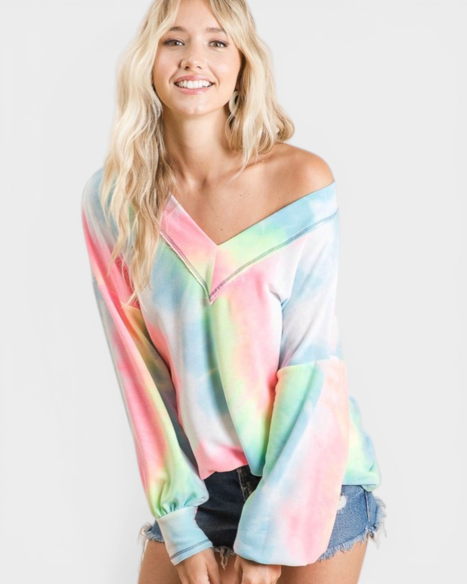 Woman wearing a colorful tie-dye off-shoulder top on a white background