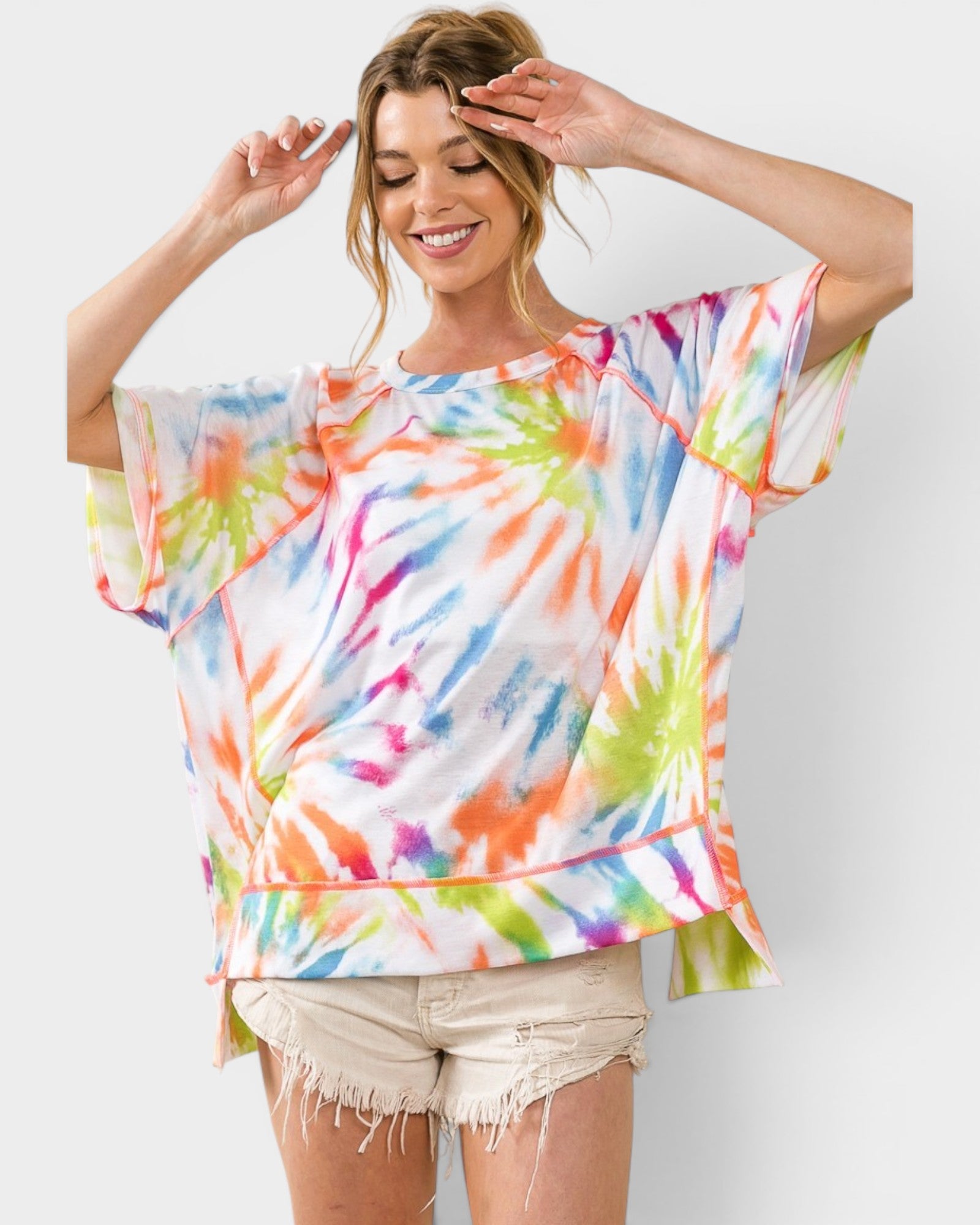 Woman wearing a colorful tie-dye shirt against a white background