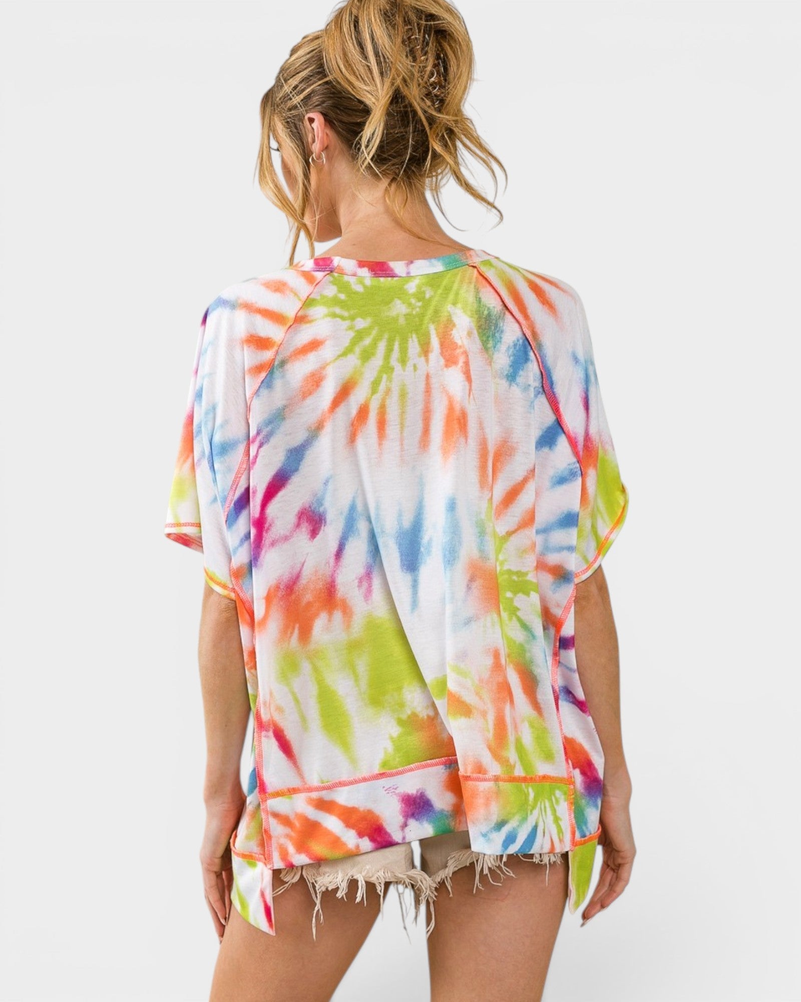 Person wearing a colorful tie-dye cover-up on a white background