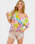 Woman wearing a colorful tie-dye off-shoulder top and shorts on a white background