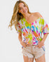 Woman wearing a colorful tie-dye off-shoulder top on a white background