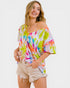 Woman wearing a colorful tie-dye off-shoulder top on a white background