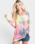 Woman wearing a colorful tie-dye long-sleeve shirt and denim shorts on a white background